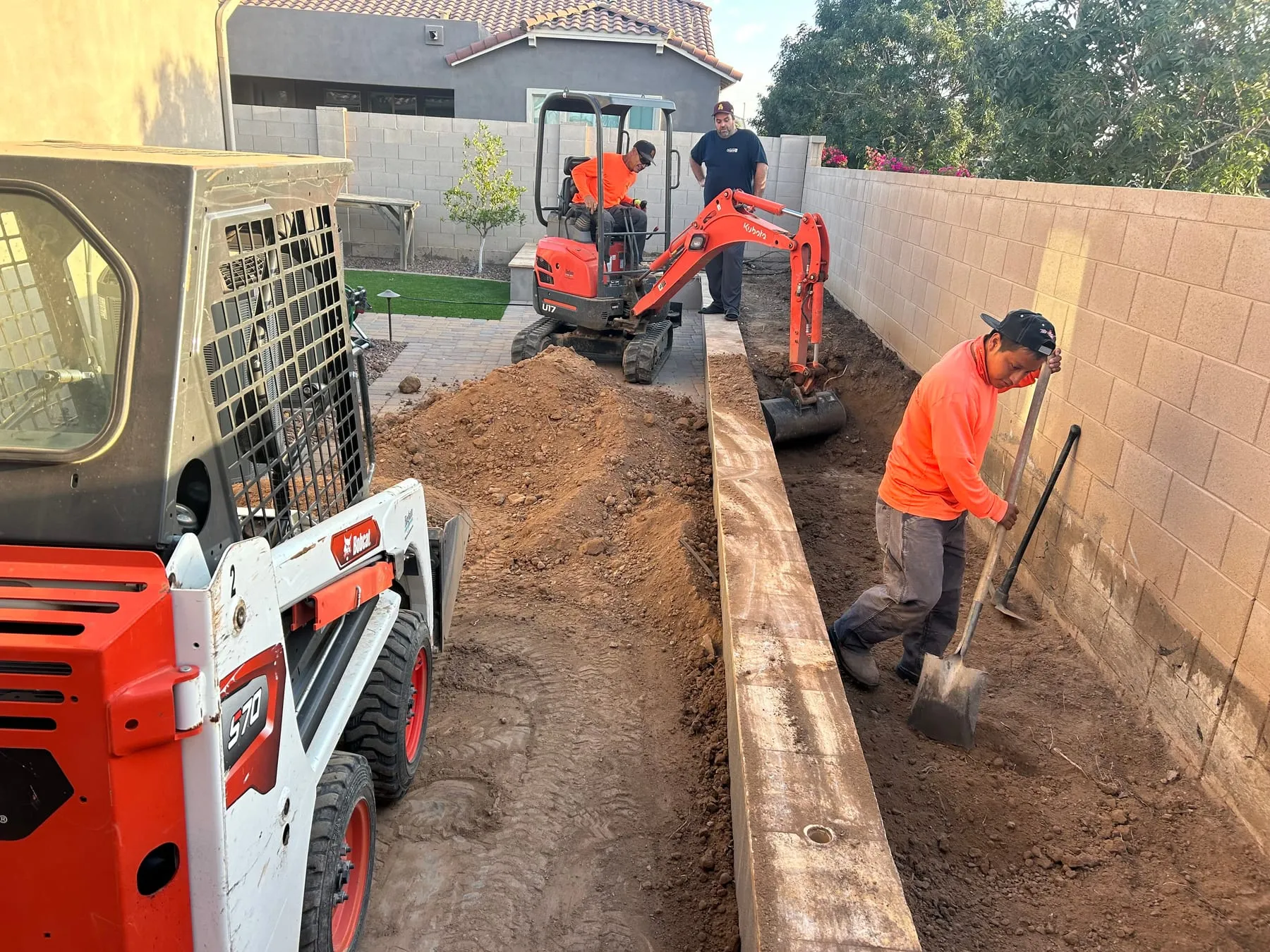 Crew operating a mini excavator to trench a backyard for a new irrigation line